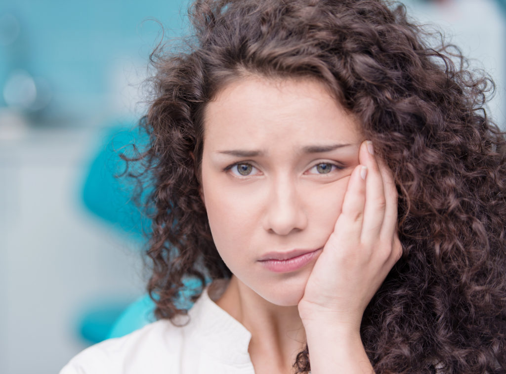 woman holding her mouth because of tooth pain